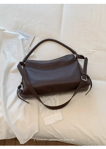 Close-up of retro brown lychee leather texture and silver buckle on the shoulder bag