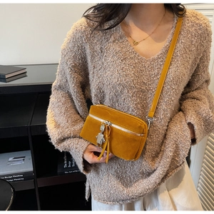Detail of mustard yellow suede crossbody box bag with metal robot pendant and tassel