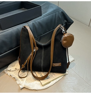 Detail of minimalist black suede tote bag with contrast stitching and small coin purse