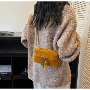 Detail of mustard yellow suede mini crossbody bag with a cute metal robot charm pendant