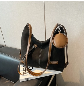Detail of black suede hobo bag with brown straps and a round coin purse on fashion books
