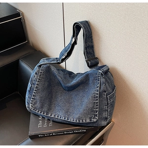 Dettaglio borsa a tracolla in denim blu con cinghia regolabile su divano