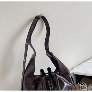 Detail of chocolate brown bucket bag featuring sleek PU leather and drawstring closure