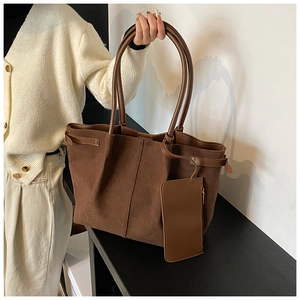 Détails de la texture du cabas en daim marron foncé avec une petite pochette assortie