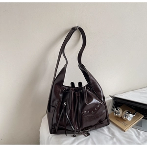 Detail view of a vintage dark brown bucket bag with glossy texture and silver rivet studs