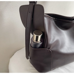 Close-up of dark brown soft leather tote bag showing side pocket detail and texture