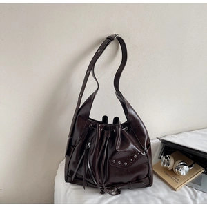 Detail of dark brown tote bag featuring silver rivets and glossy leather texture