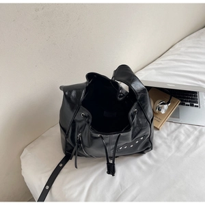 Top view of shiny black leather drawstring bucket bag with side zippers and metal studs