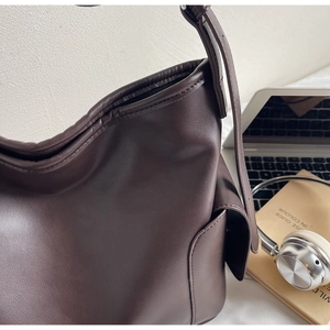 Detailed macro view of smooth dark brown leather texture and side pocket on tote bag