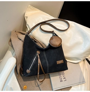 Detail of black suede tote bag with contrast stitching and brown leather coin purse