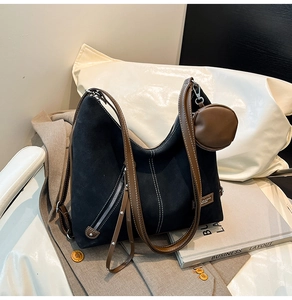 Detail of black suede tote bag with brown leather straps and contrast stitching accents