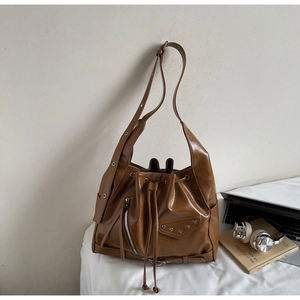 Detail of a brown leather Hobo bag with adjustable eyelet strap and metallic rivet accents