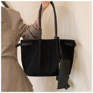 Détail d'un sac cabas en daim noir avec lanières en cuir et petite pochette amovible