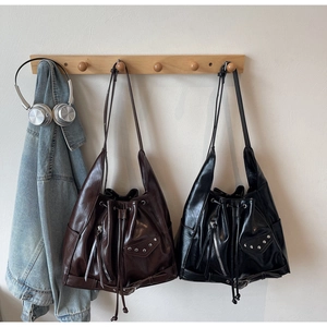 Detail view of vintage bucket bags with glossy finish, metal rivets and zipper accents