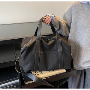 Detail of the black minimalist tote bag showing matte texture and PU leather straps