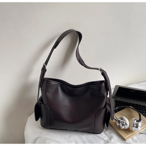Detail view of deep brown PU tote bag with side flap pockets and silver metal buckles