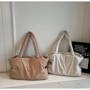 Close-up of quilted puffer tote bags in caramel and off-white with padded straps