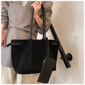 Détail du sac cabas noir en daim avec pochette zippée assortie porté par un mannequin