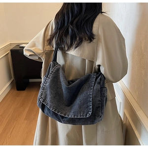 Dettaglio borsa a tracolla in denim nero lavato con patta e tasche laterali indossata