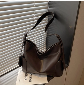 Detail view of large dark brown leather tote featuring side pockets and metal strap buckle