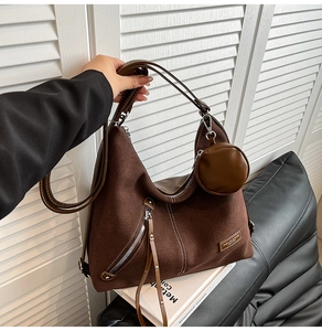 Detail of dark brown suede hobo bag with fringe zipper and round coin purse charm