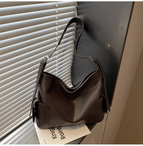 Detail view of smooth dark brown PU leather texture and adjustable strap on a tote bag
