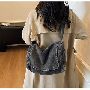 Vista posteriore della modella che indossa una grande borsa messenger in denim grigio scuro