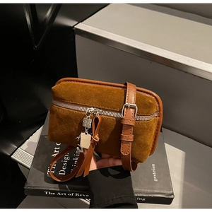 Detailed close-up of brown suede crossbody bag with robot charm and leather tassel