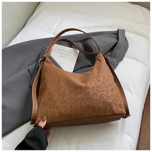 Macro detail of brown leopard print tote bag with white stitching on soft suede fabric