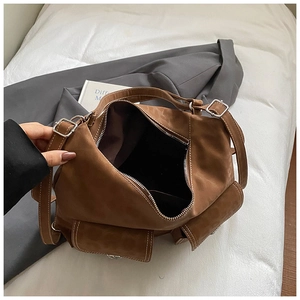 Detail view of large brown leather tote bag with contrast stitching and multi pockets