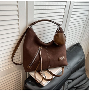 Macro shot of large dark brown suede hobo bag with silver zipper and mini round pouch