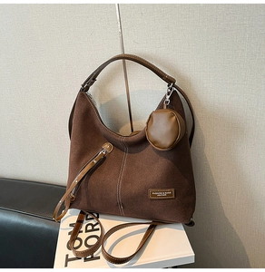 Detail of dark brown suede tote bag with white stitching and round coin purse accessory