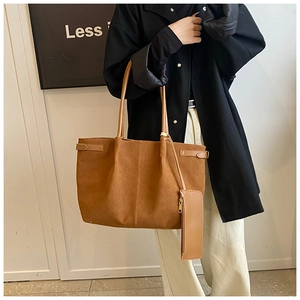 Sac fourre-tout en daim marron avec pochette assortie porté par un mannequin