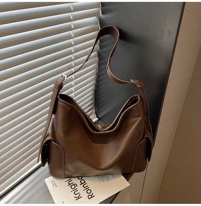 Close-up of brown PU leather tote bag with functional side pocket and wide shoulder strap