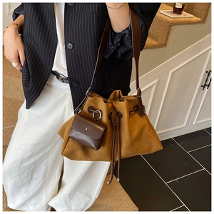 Detail view of brown suede bucket bag with leather drawstring and matching mini pouch