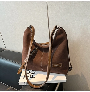 Detail of coffee brown suede hobo bag with white contrast stitching on a book