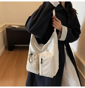 Λεπτομέρεια από νάιλον τσάντα χιαστί σε off-white με λειτουργικές τσέπες με κορδόνι