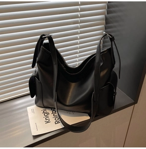 Macro detail of black PU leather hobo bag with side pockets and wide adjustable strap