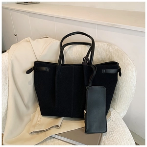 Gros plan d'un cabas en daim noir avec pochette assortie sur un fond neutre et doux
