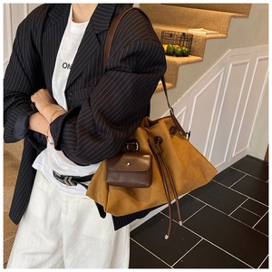 Caramel drawstring bucket bag in suede finish styled on model at indoor stairs