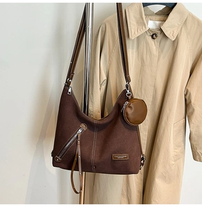 Detail of dark brown leather tote bag with silver zippers and mini coin purse hanging