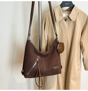 Detailed view of dark brown suede hobo bag with contrast stitching and mini round pouch