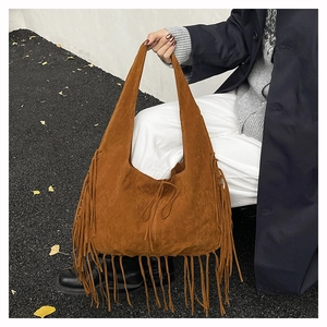Detailed close-up of brown suede fringe tote bag with long tassels and drawstring closure