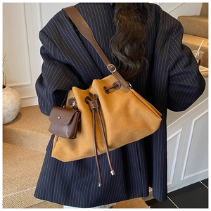 Close-up of vintage mustard suede bucket bag with drawstring and wide leather strap