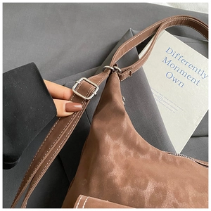 Detail of brown leather shoulder bag featuring white stitching and silver buckle adjustment