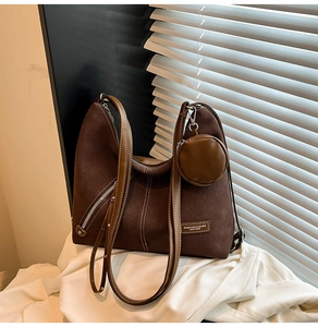 Close-up of brown suede tote bag featuring a round coin purse and metal zipper detail
