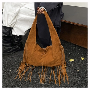 Close-up of brown suede shoulder bag featuring long fringe tassels and tie closure
