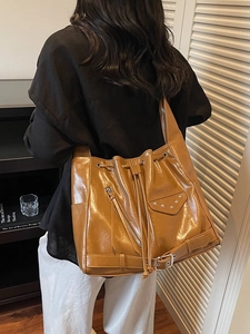 Retro brown leather bucket bag with drawstring closure and silver hardware on model
