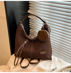 Detail of dark brown suede tote bag with contrast stitching and small round pouch