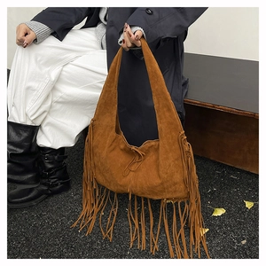 Close-up of caramel suede hobo bag featuring long tassels and bohemian fringe details